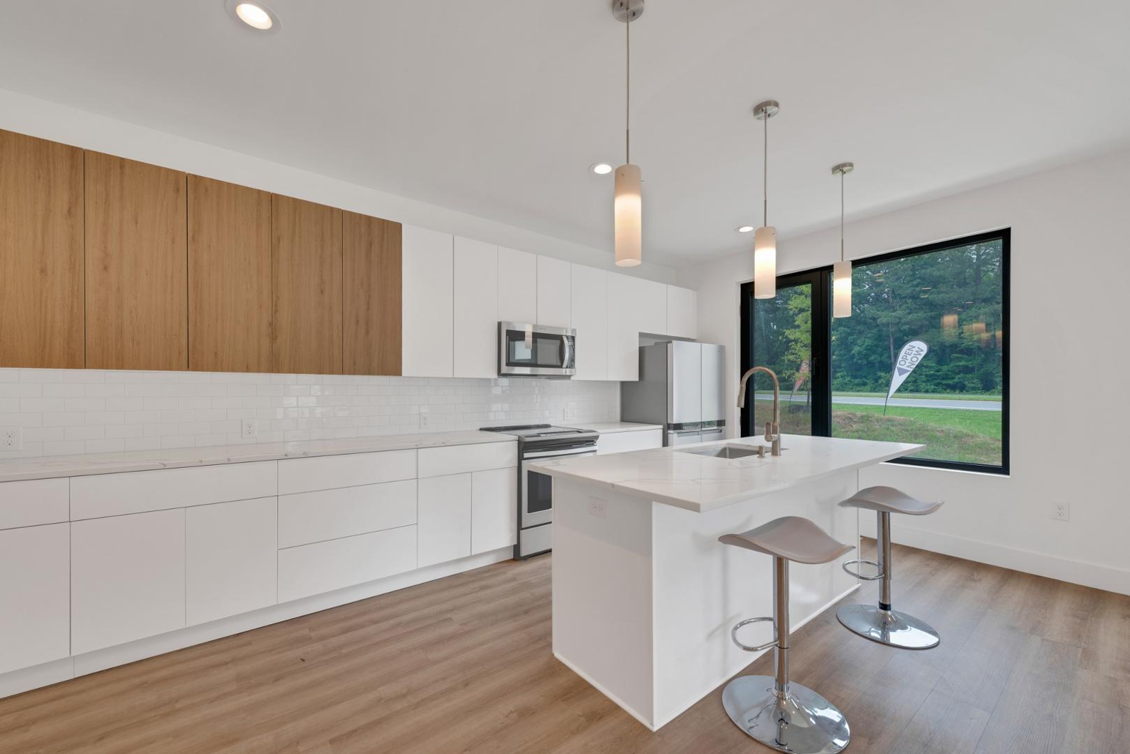 2013 Jade Street Durham, NC 27713 - Photo 8 of 31 a kitchen with stainless steel appliances granite countertop a stove a sink a microwave a dining table and chairs with wooden floor