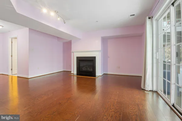 an empty room with wooden floor fireplace and windows