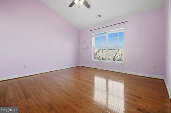 an empty room with wooden floor chandelier fan and windows