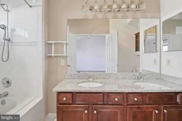 a bathroom with a granite countertop sink a mirror and a bathtub