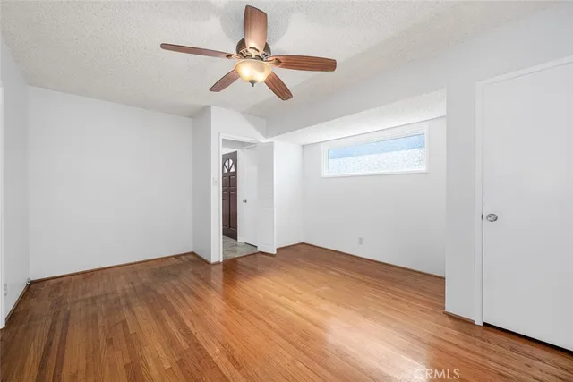 an empty room with wooden floor fan and windows