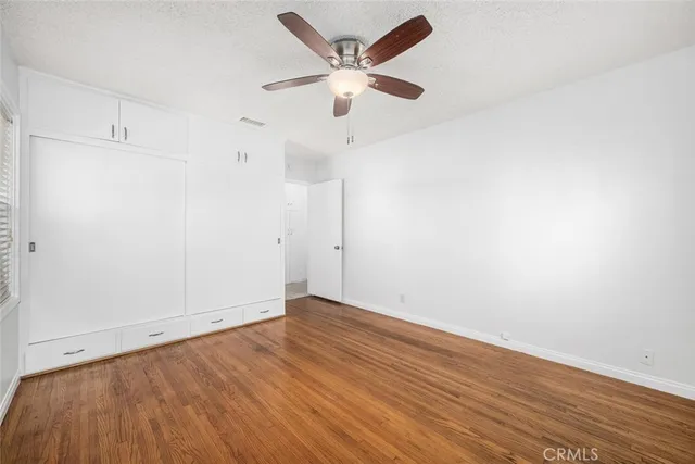 an empty room with wooden floor and ceiling fan
