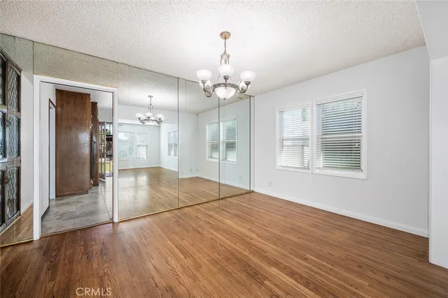 a view of an empty room with wooden floor and a kitchen