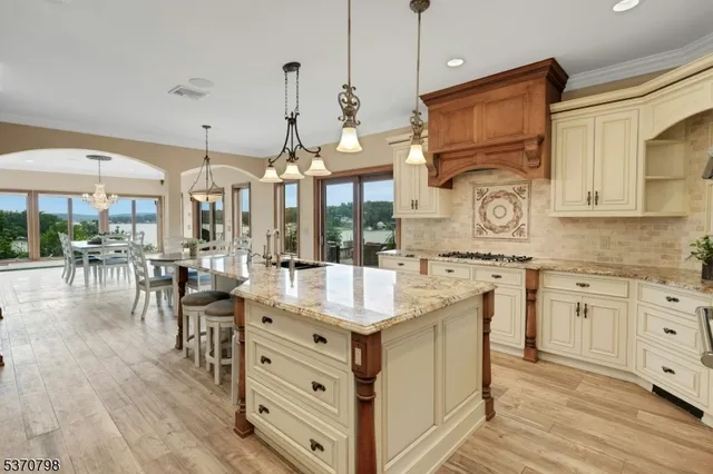 a kitchen with stainless steel appliances granite countertop a sink dishwasher a stove and a dining table with wooden floor