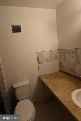 a bathroom with a granite countertop sink and a toilet