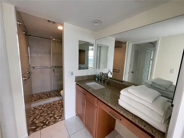 a bathroom with a granite countertop sink a toilet a mirror and shower
