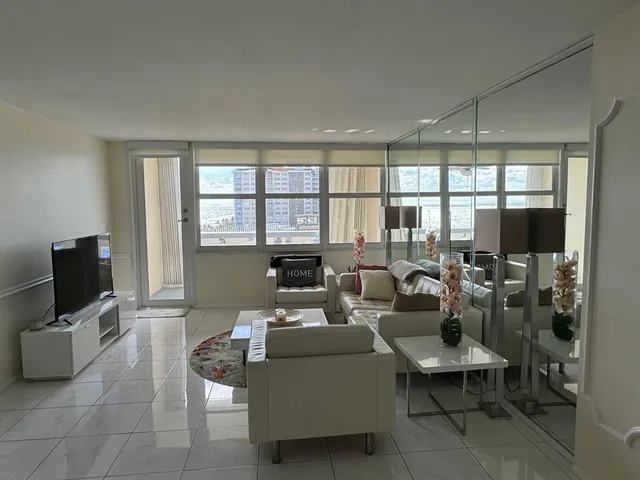 a living room with furniture a flat screen tv and a floor to ceiling window