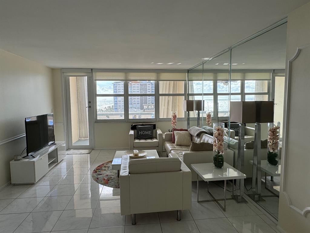 305 North Pompano Beach Boulevard, Unit 1006 Pompano Beach, FL 33062 - Photo 10 of 42 a living room with furniture a flat screen tv and a floor to ceiling window