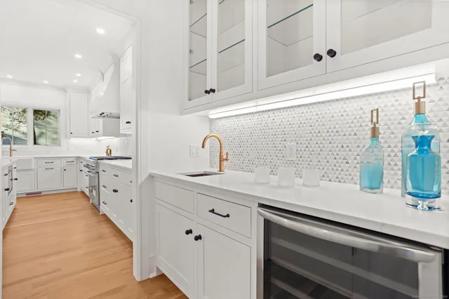 a large white kitchen with lots of counter space and wooden floor
