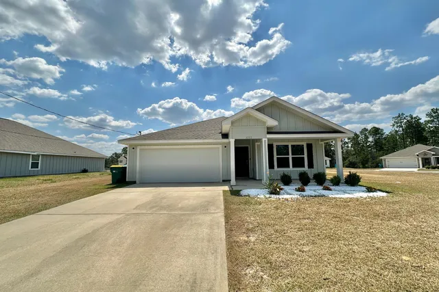 a front view of house with yard and trees in the background