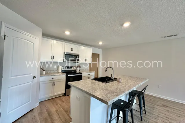 a kitchen with granite countertop stainless steel appliances a sink and a refrigerator