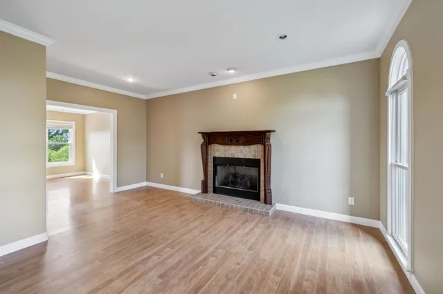 a view of an empty room with wooden floor and windows