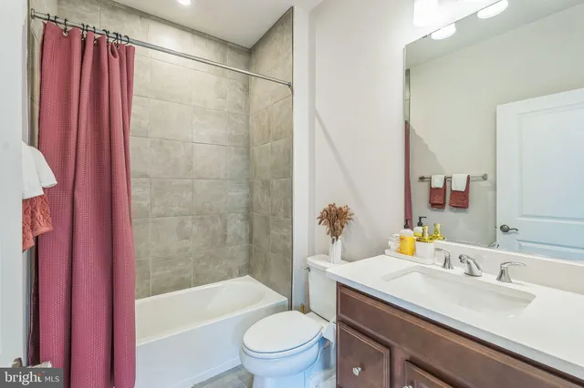 a bathroom with a sink a toilet a mirror a bathtub and shower