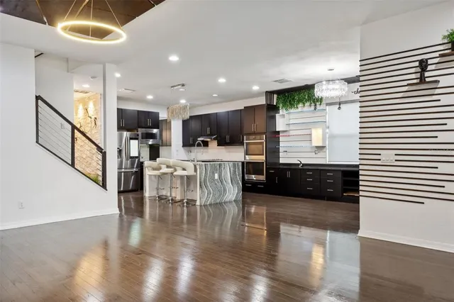 a kitchen with stainless steel appliances a dining table chairs and white walls with wooden floor