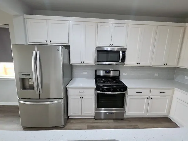 a kitchen with a refrigerator stove and white cabinets