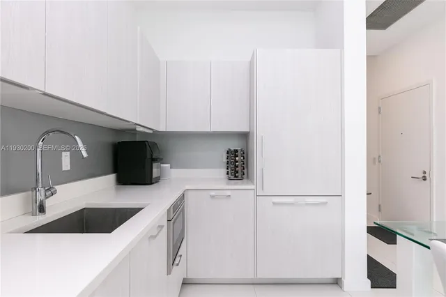 a kitchen with a stove a sink and white cabinets