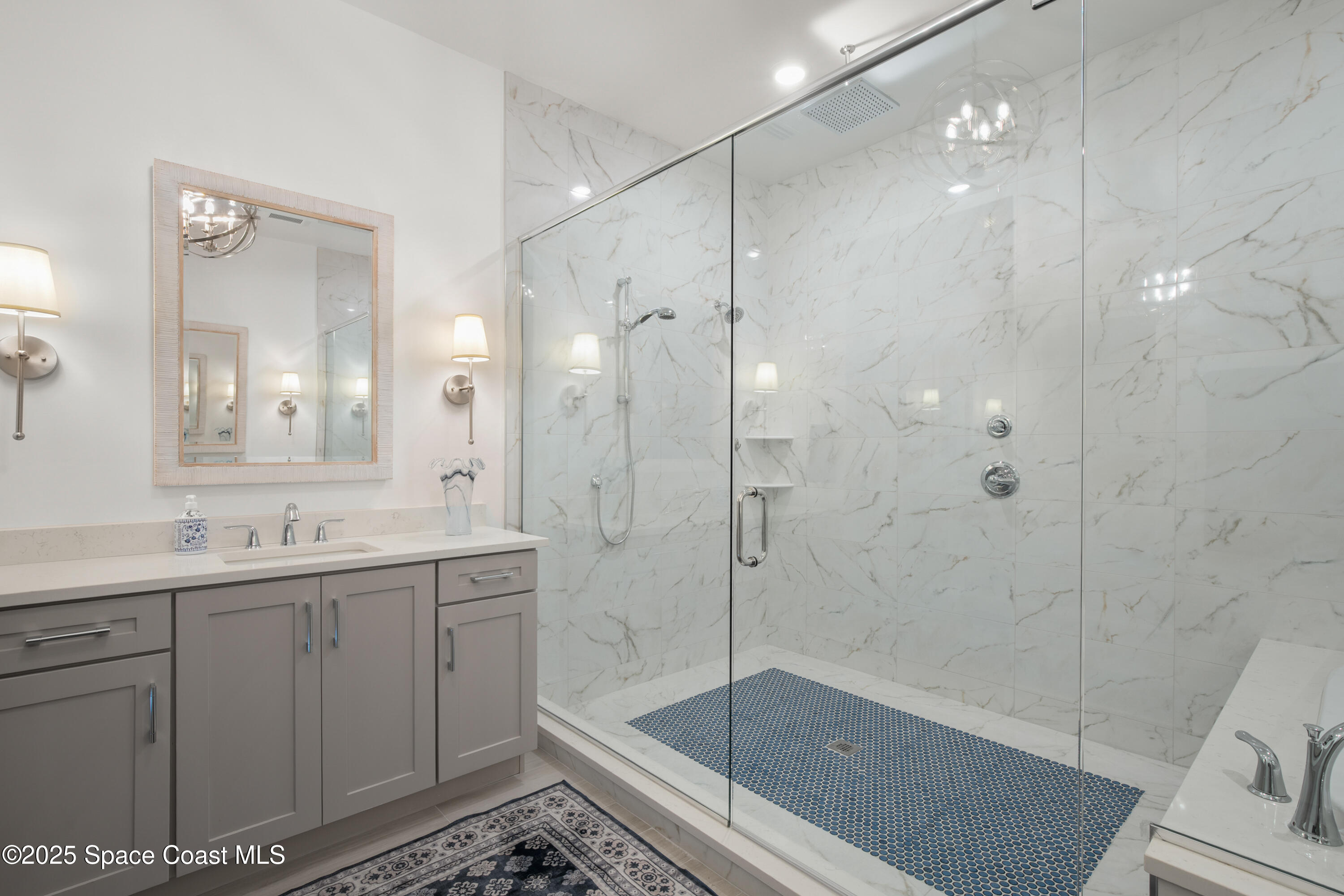 225 Strand Drive, Unit 406 Melbourne Beach, FL 32951 - Photo 23 of 49 a bathroom with a shower sink vanity and mirror