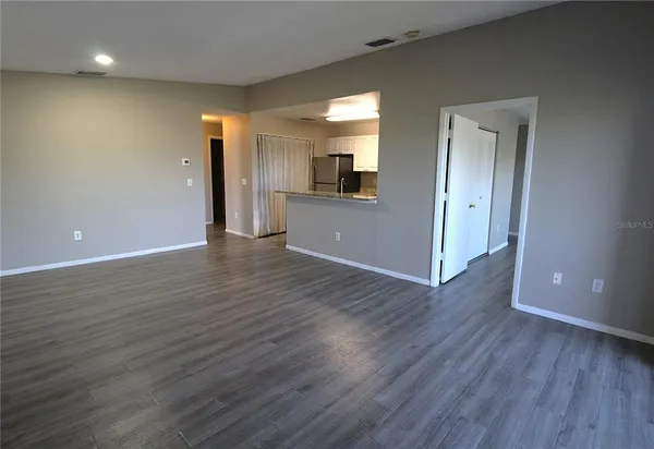 a view of a hallway with wooden floor and a bathroom