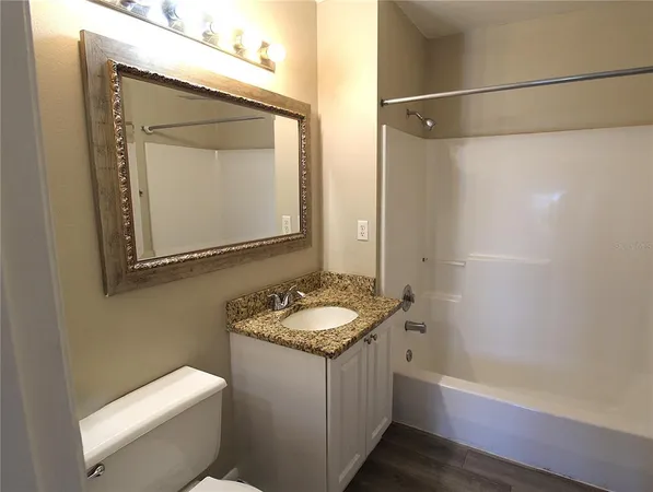 a bathroom with a granite countertop sink toilet and mirror