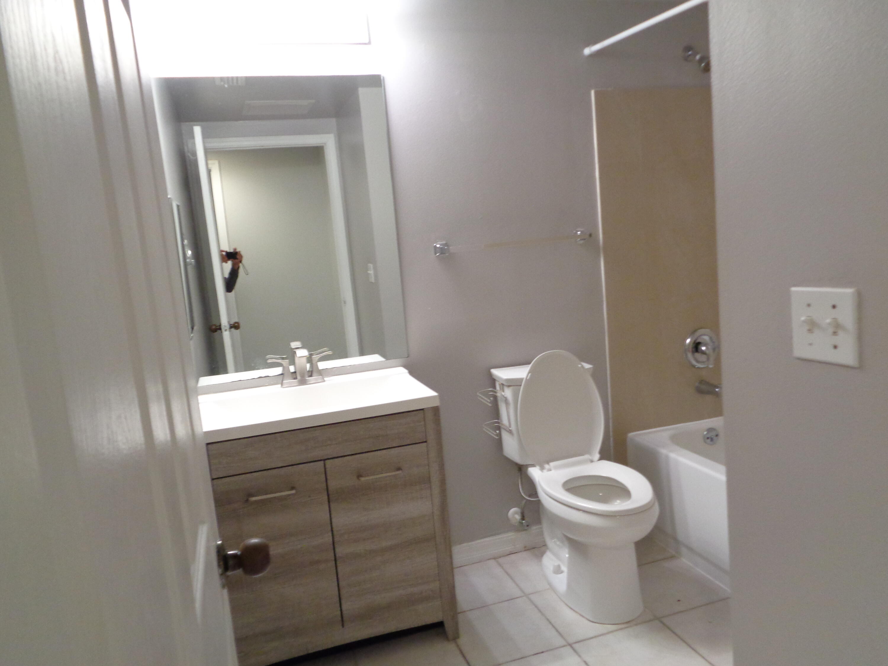 10354 Fox Trail Road South, Unit 1509 Royal Palm Beach, FL 33411 - Photo 10 of 13 a bathroom with a toilet a sink and mirror