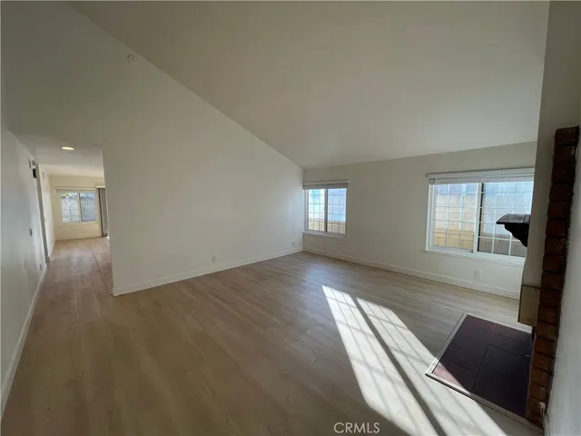 a view of an empty room with wooden floor and a windows