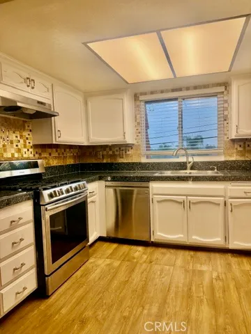 a kitchen with granite countertop a stove a sink and a microwave