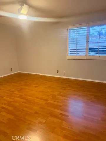 a view of an empty room with window and wooden floor