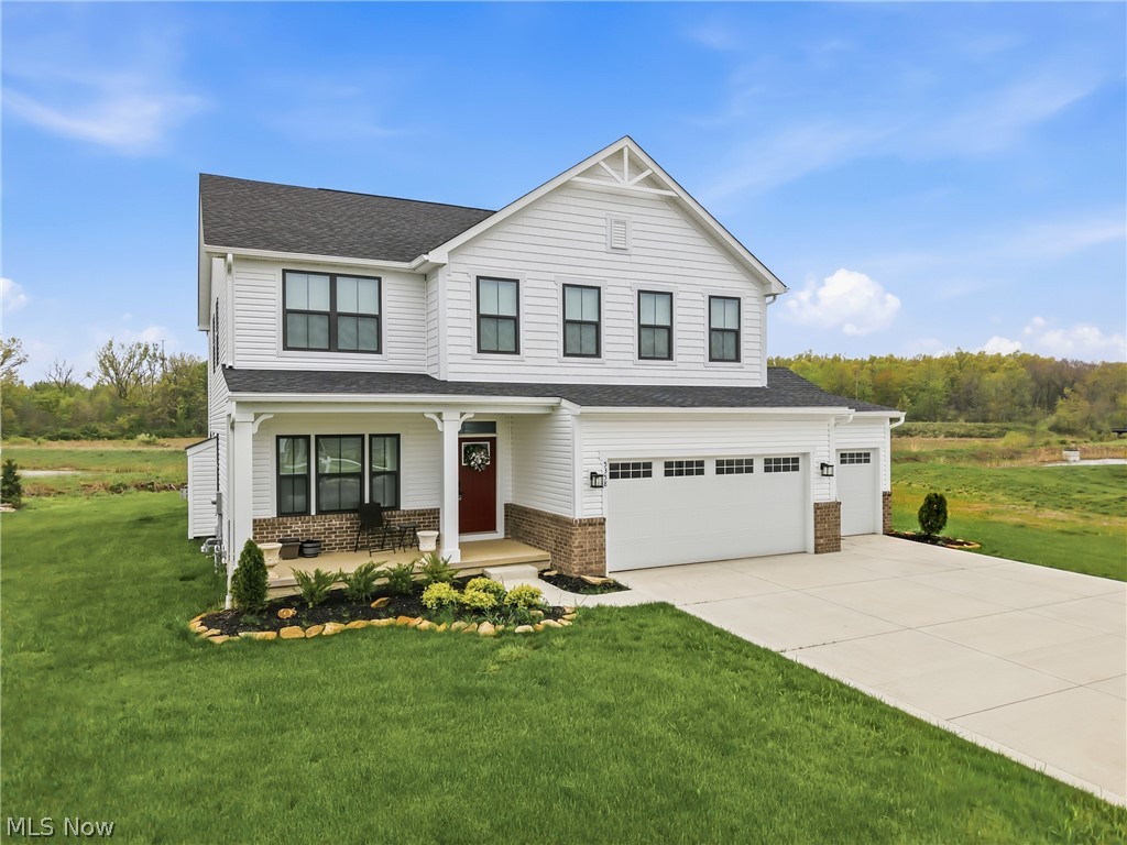 5358 Walnut Rdg Lane Sheffield Lake, OH 44054 - Photo 2 of 50 Contemporary two-story exterior featuring white siding with brick accents, a dark-shingled roof, a three-car garage, and a covered front porch with a red entry door