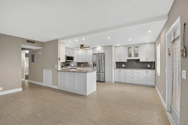 a kitchen with granite countertop white cabinets and stainless steel appliances