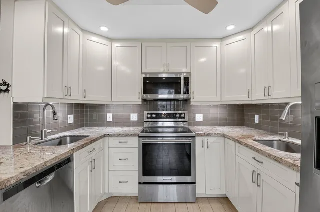 a kitchen with stainless steel appliances granite countertop a stove a sink and a refrigerator