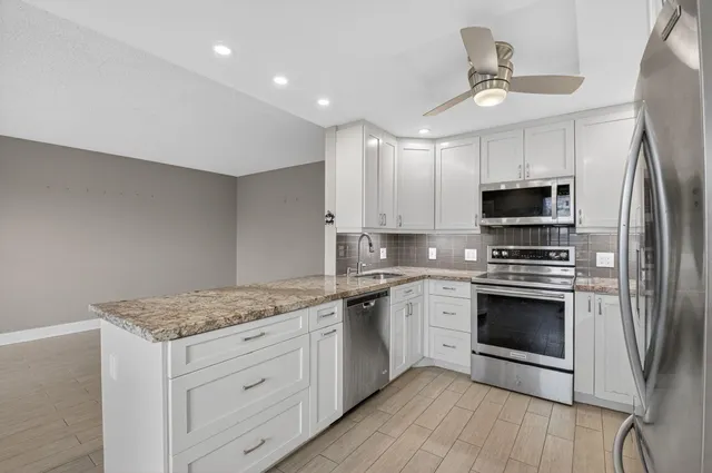a kitchen with stainless steel appliances kitchen island granite countertop a refrigerator and a sink