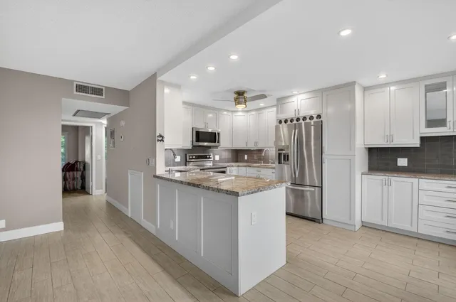 a kitchen with stainless steel appliances granite countertop a refrigerator a stove a microwave oven a sink with dishwasher and refrigerator