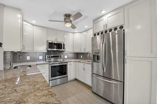 a kitchen with stainless steel appliances granite countertop a stove a sink and a refrigerator