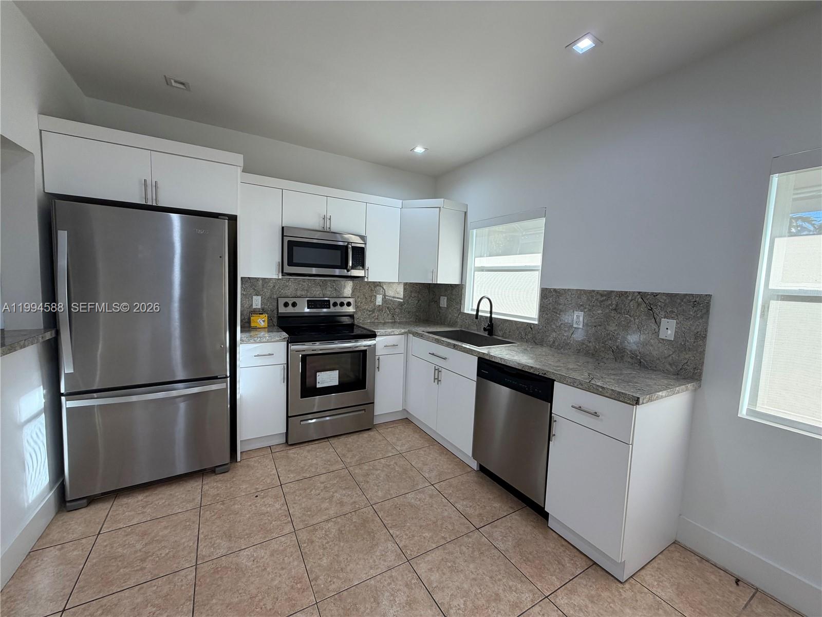 3373 Southwest 29th Terrace Miami, FL 33133 - Photo 20 of 26 a kitchen with granite countertop a refrigerator and a stove top oven