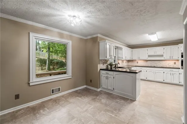 a kitchen with a stove a sink dishwasher a refrigerator and white cabinets with wooden floor