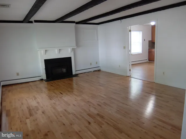 an empty room with wooden floor and fireplace