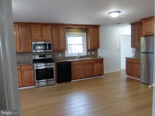 a kitchen with stainless steel appliances granite countertop a stove a sink and a refrigerator