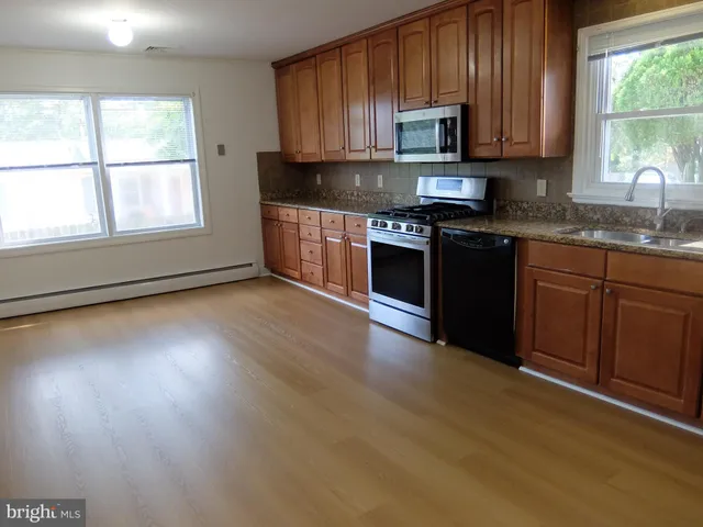 a kitchen with granite countertop wooden cabinets a stove a microwave and a window