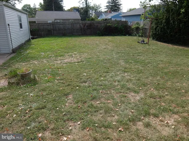 a view of a white house with a small yard and a large tree