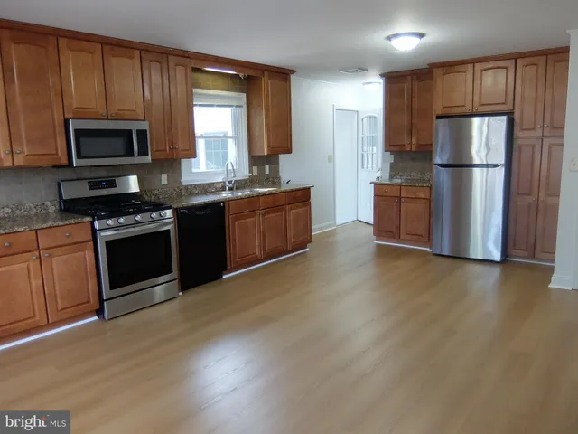 a kitchen with granite countertop a refrigerator a stove top oven a sink and dishwasher