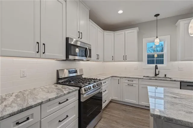 a kitchen with granite countertop a sink stainless steel appliances and cabinets