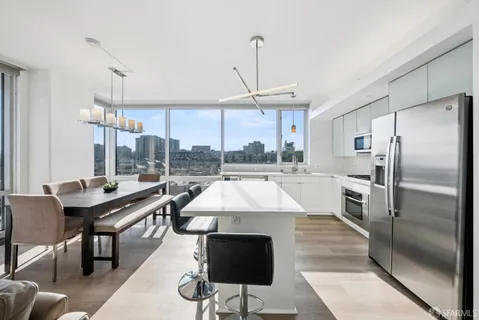 a view of a dining room with furniture a chandelier and large windows