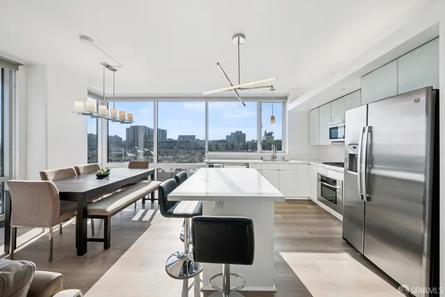 a view of a dining room with furniture a chandelier and large windows