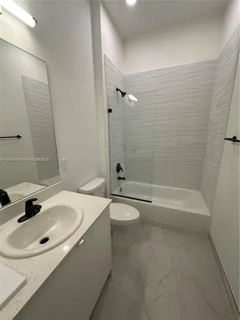 a kitchen with granite countertop a refrigerator and wooden floor