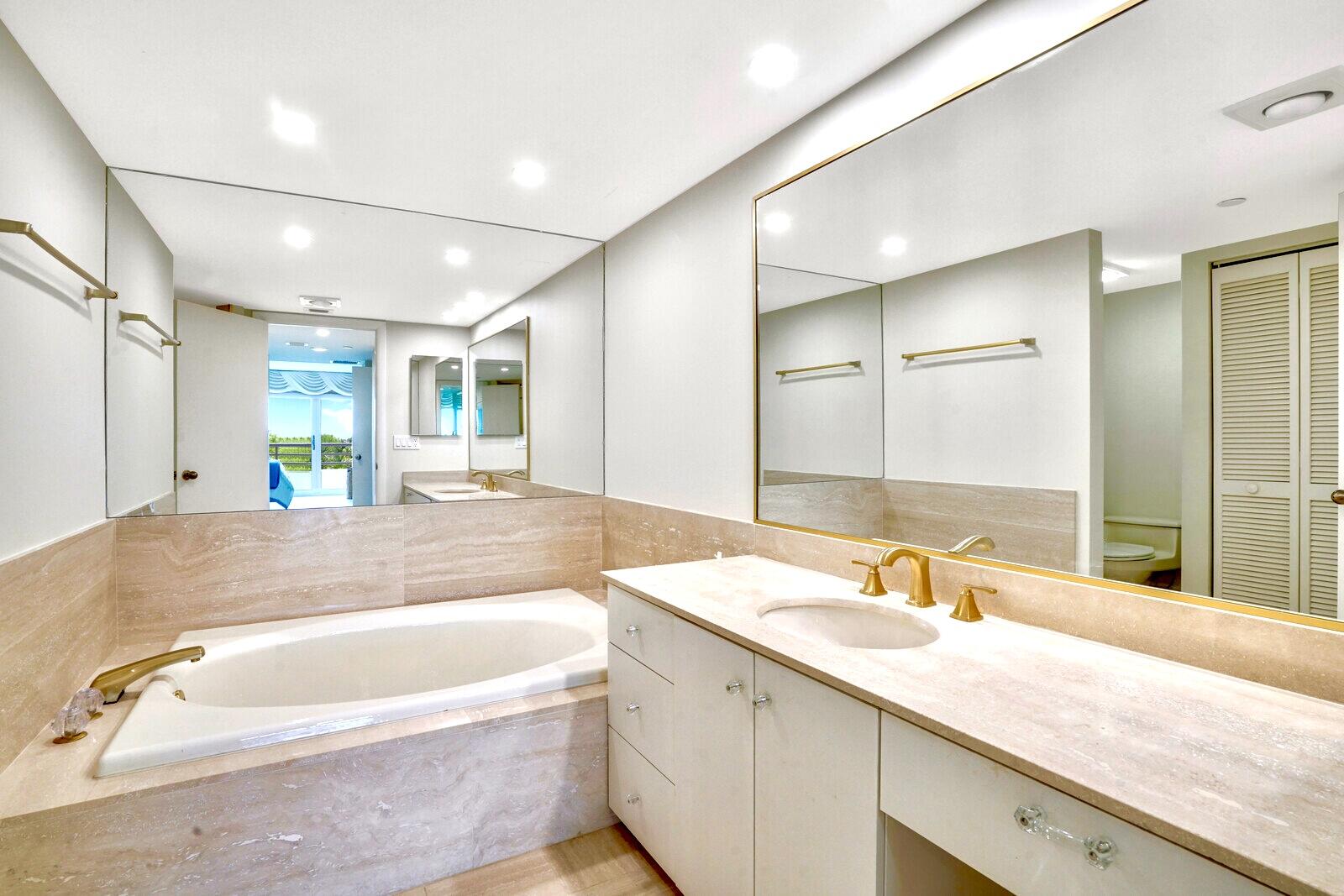4101 North Ocean Boulevard, Unit D408 Boca Raton, FL 33431 - Photo 23 of 31 a bathroom with a granite countertop tub sink and mirror
