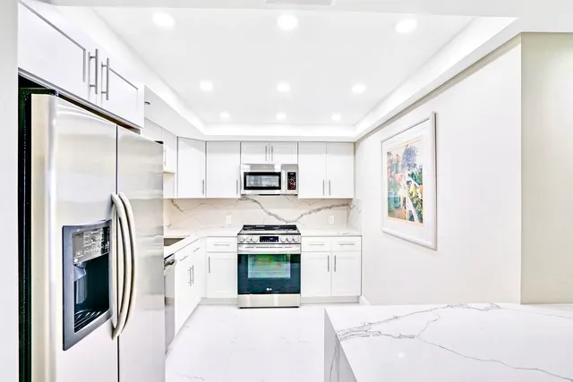 a kitchen with stainless steel appliances granite countertop a refrigerator a stove and a sink