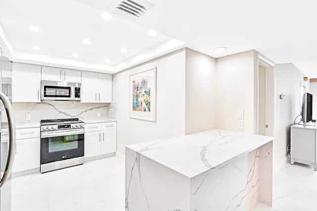 a kitchen with stainless steel appliances white cabinets a sink a stove a refrigerator and white cabinets