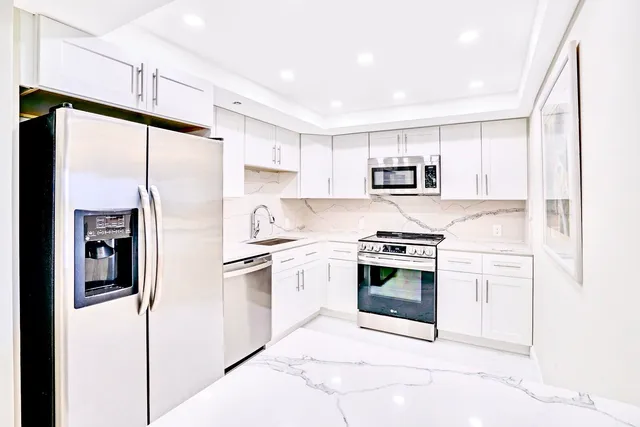 a kitchen with stainless steel appliances granite countertop a refrigerator stove oven and sink