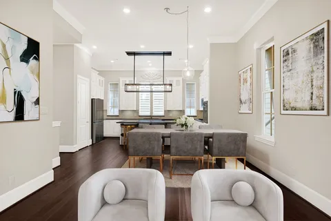 a living room with furniture kitchen view and a wooden floor
