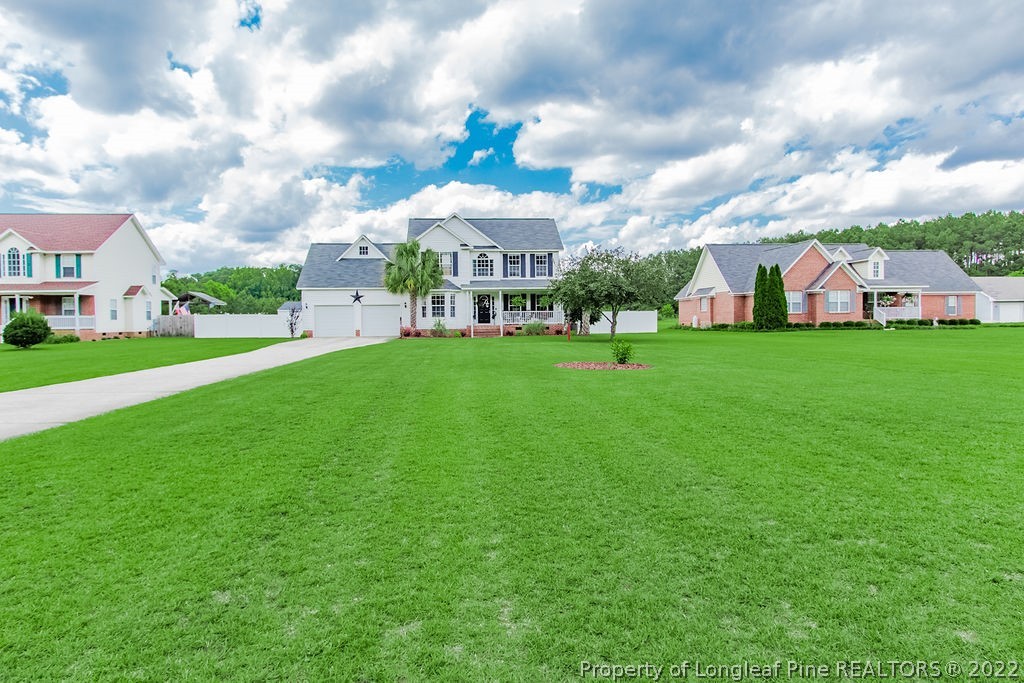 1105 John McMillan Road Hope Mills, NC 28348 - Photo 2 of 50 a view of a white house in front of a big yard with plants and large trees